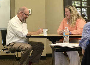 Dr. Robin McWilliam talks with a woman while taking notes.